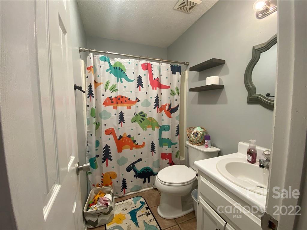 104 Dameron Road Bessemer City, NC 28016 - Photo 13 of 15 a white toilet sitting next to a bathroom sink and a shower curtain