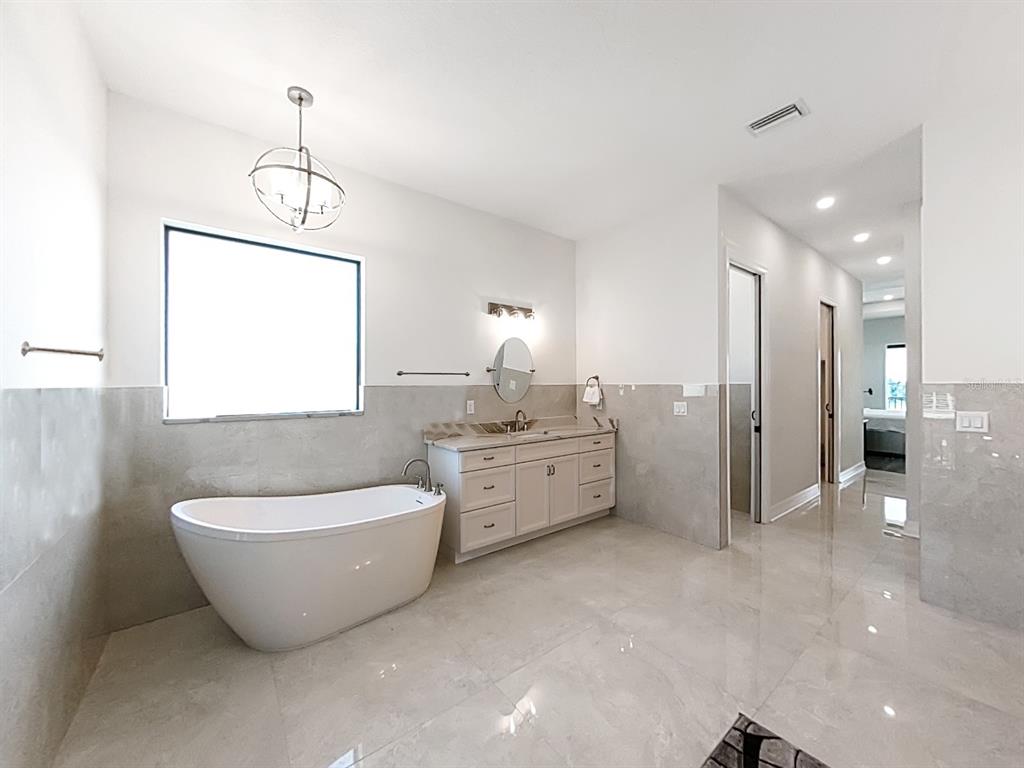 882 Bay Point Drive Madeira Beach, FL 33708 - Photo 30 of 73 a spacious bathroom with a double vanity sink a mirror and a bathtub