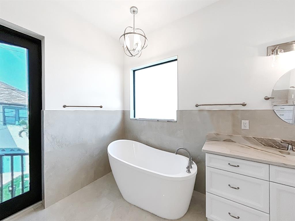 882 Bay Point Drive Madeira Beach, FL 33708 - Photo 31 of 73 a bathroom with a granite countertop sink mirror vanity and bathtub