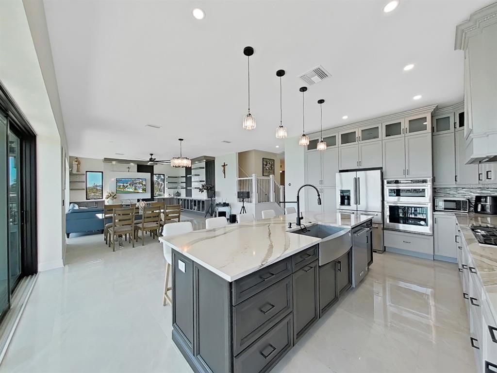882 Bay Point Drive Madeira Beach, FL 33708 - Photo 6 of 73 a large white kitchen with sink a stove and chairs