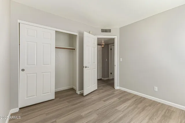 an empty room with wooden floor and closet area