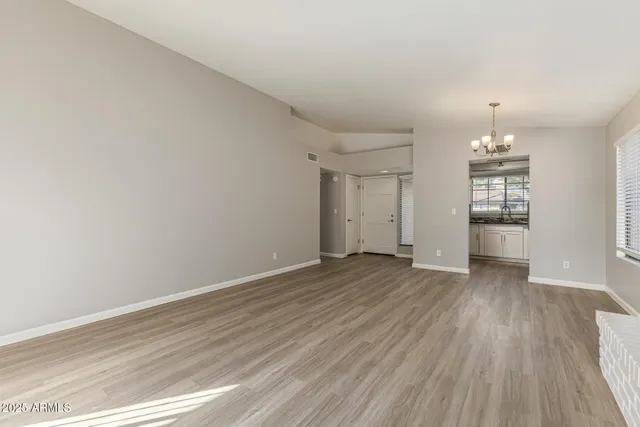an empty room with wooden floor and window