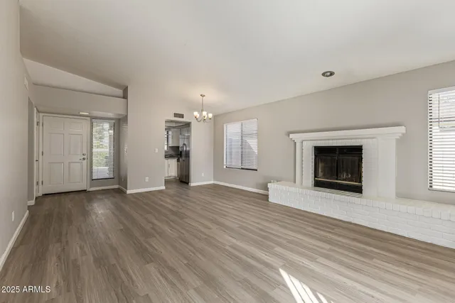 an empty room with wooden floor fireplace and windows