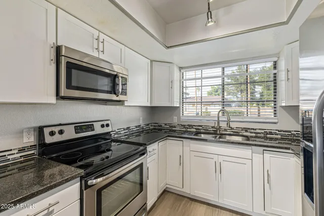 a kitchen with stainless steel appliances granite countertop a sink stove and microwave