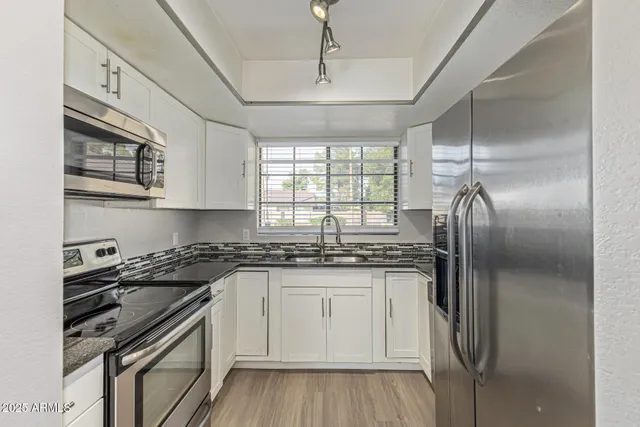 a kitchen with stainless steel appliances granite countertop a sink stove and refrigerator