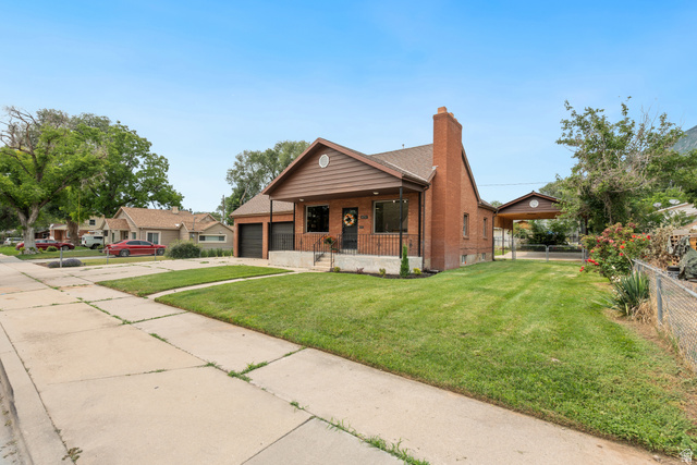 673 East 700 South Springville, UT 84663 - Photo 2 of 43 Traditional brick facade home featuring a covered front porch, an attached two-car garage, and a side carport
