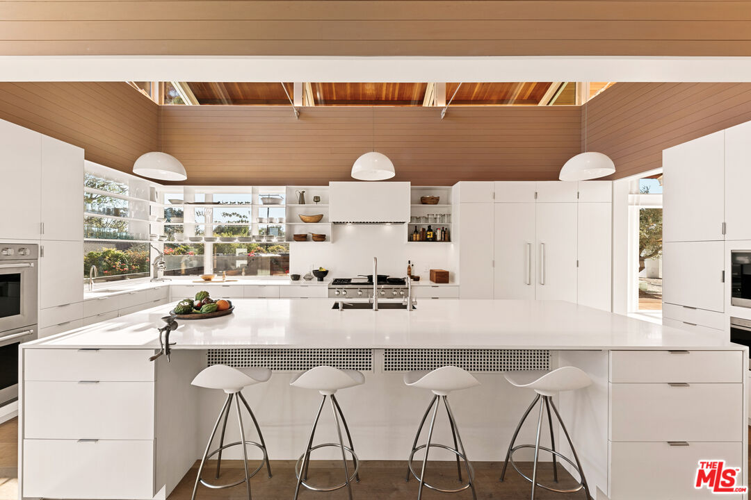 6728 Wildlife Road Malibu, CA 90265 - Photo 11 of 57 a kitchen with a sink and white cabinets with wooden floor