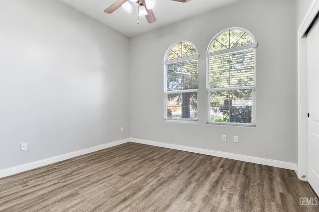 an empty room with wooden floor chandelier and windows