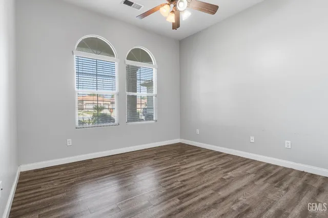 a view of empty room with wooden floor and fan