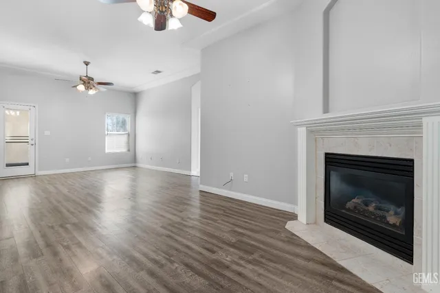 a view of an empty room with wooden floor fireplace and a window