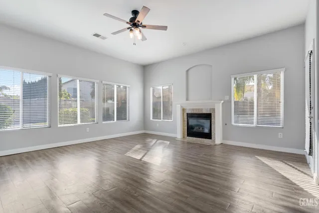 a view of an empty room with wooden floor fireplace and a window