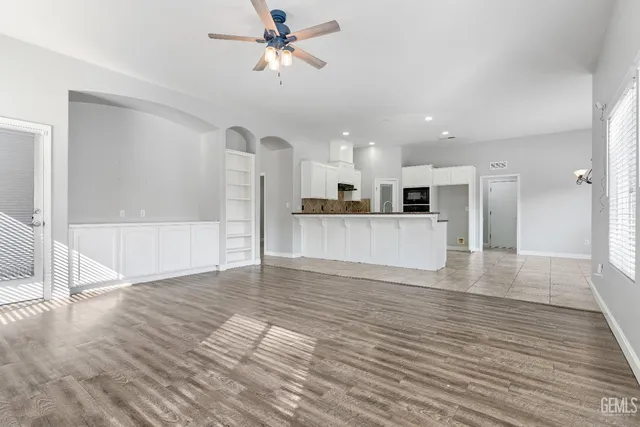 a view of a big room with wooden floor and a kitchen