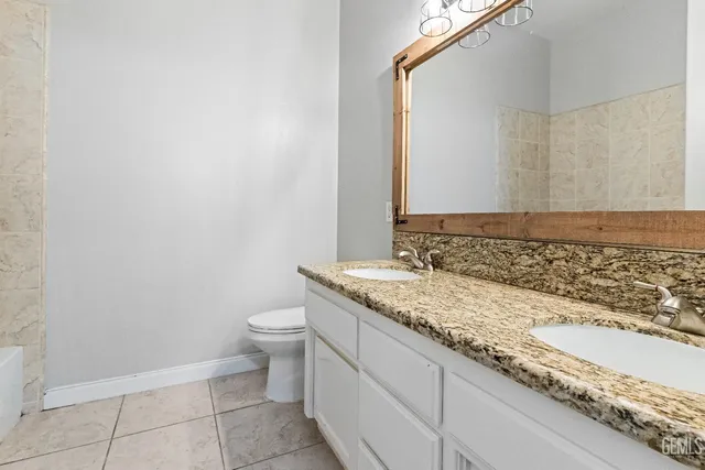 a bathroom with a granite countertop sink and a toilet