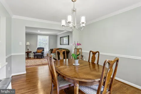 a large kitchen with a refrigerator a sink dishwasher a stove and white cabinets with wooden floor