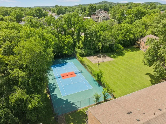 an aerial view of residential houses with outdoor space and trees all around