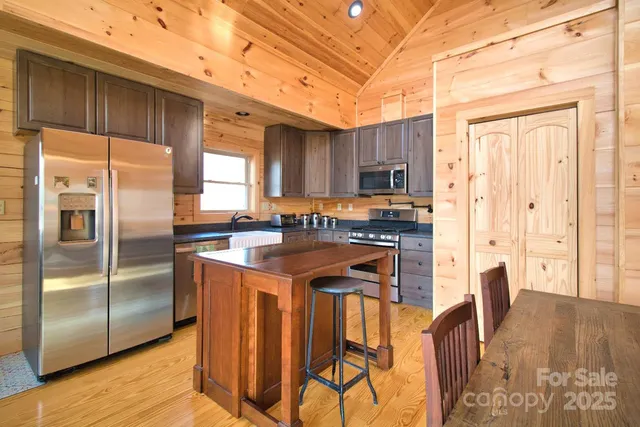 a kitchen with granite countertop a refrigerator a sink a stove and chairs with wooden floor