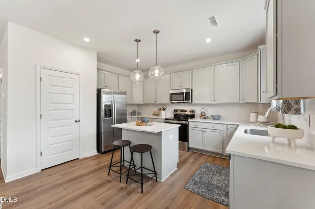 a kitchen with kitchen island granite countertop a sink cabinets and wooden floor