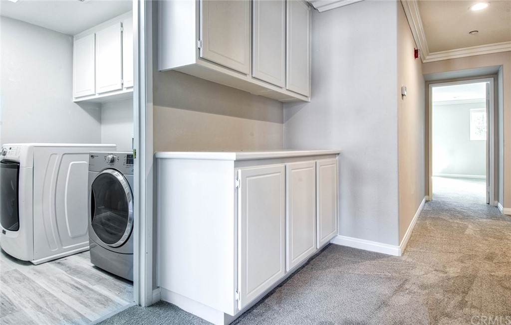 83 Sapphire, Unit 46 Irvine, CA 92602 - Photo 14 of 18 a view of washer and dryer with kitchen in the background