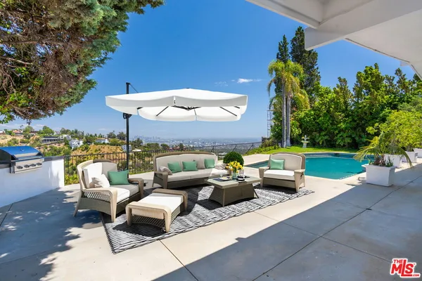 a view of a patio with couches table and chairs under an umbrella with a fire pit