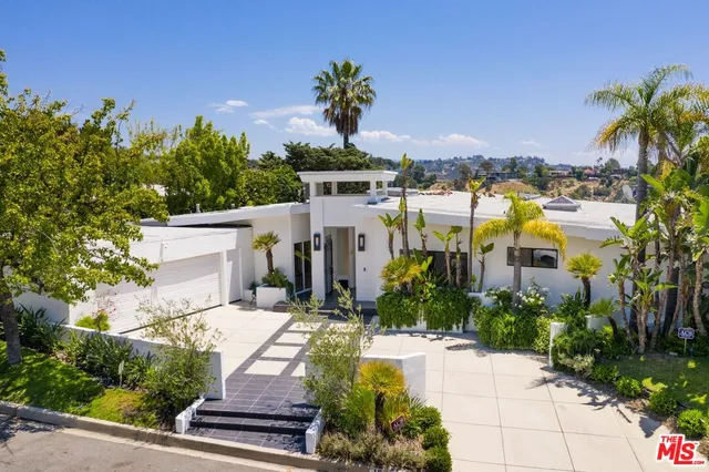 a view of a white building with a flower garden