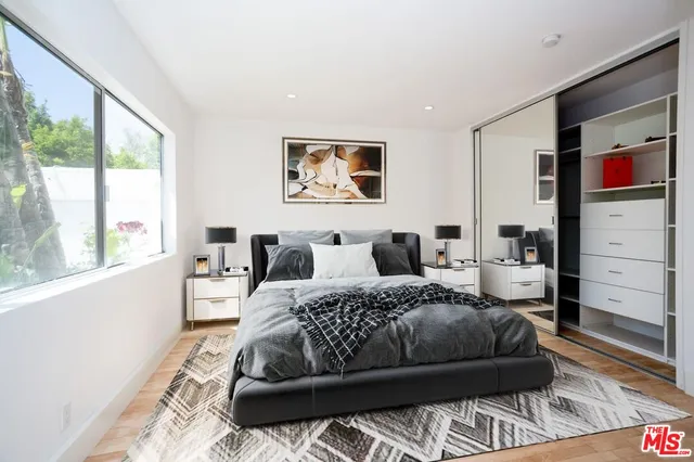 a bedroom with a bed a dresser and a large window
