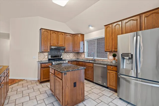 a kitchen with stainless steel appliances granite countertop a stove a refrigerator and a sink
