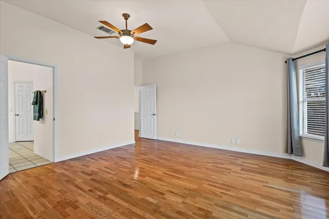 a view of an empty room with window and chandelier fan