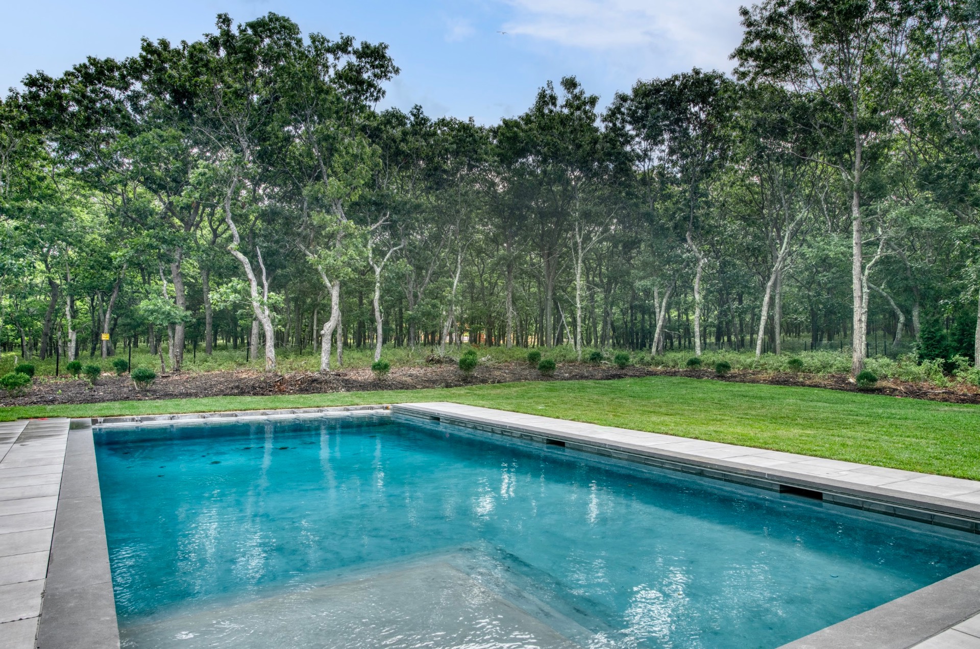 497 Toppings Path Sag Harbor, NY 11963 - Photo 3 of 12 a view of a swimming pool with a table and trees in the background