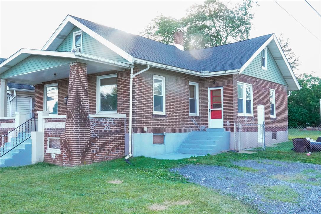 870 Chestnut Street Coplay, PA 18037 - Photo 2 of 24 A charming brick residence features a covered porch and a prominent red entry door.