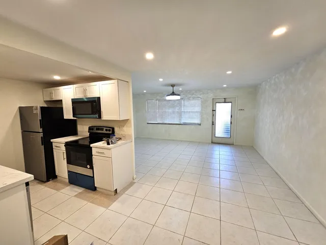 a view of a kitchen with refrigerator and white cabinets