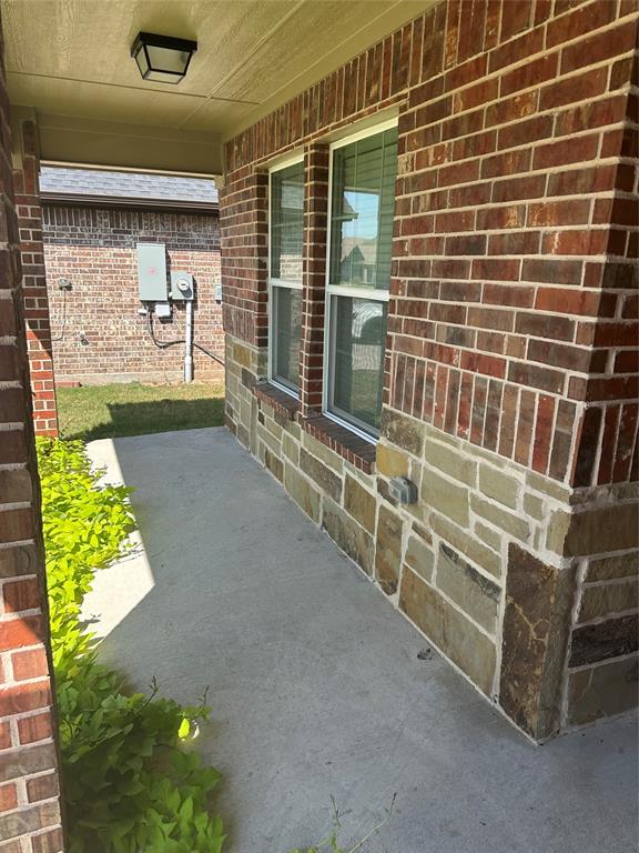 806 Ransom Way Greenville, TX 75402 - Photo 21 of 27 Brick and stone veneer exterior with double-hung windows, concrete walkway, and covered entryway