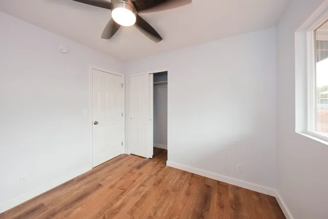 an empty room with a window and a chandelier fan