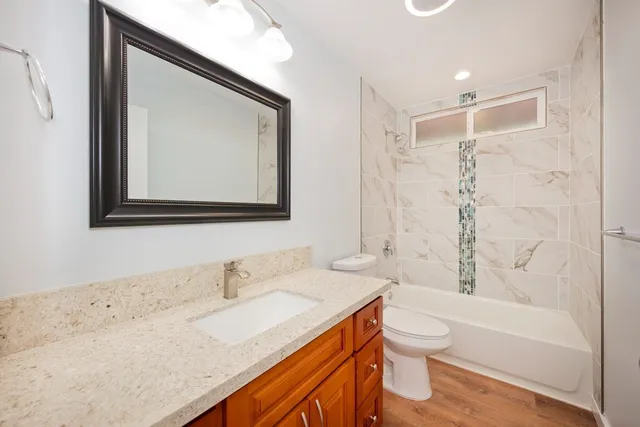 a bathroom with a granite countertop sink toilet and shower