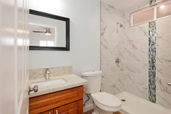 a bathroom with a granite countertop toilet sink and mirror