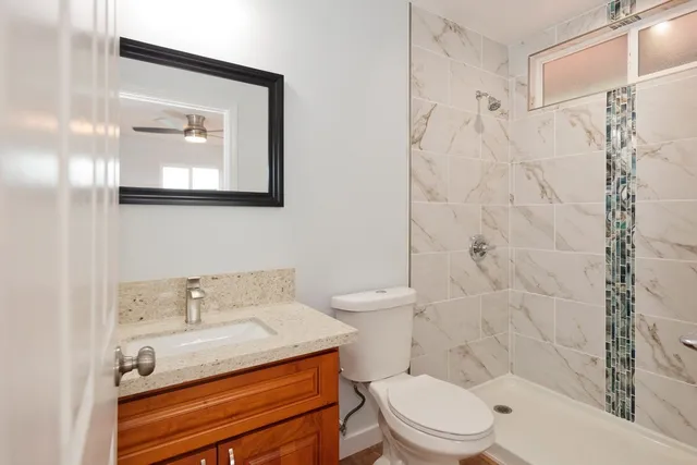 a bathroom with a granite countertop toilet sink and mirror