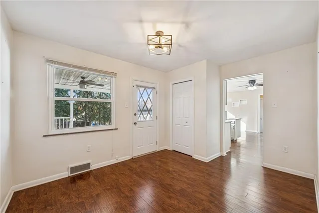 a view of an empty room with window and wooden floor