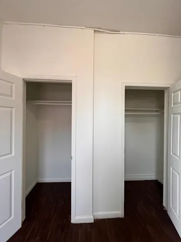 a view of an empty room with wooden floor and closet