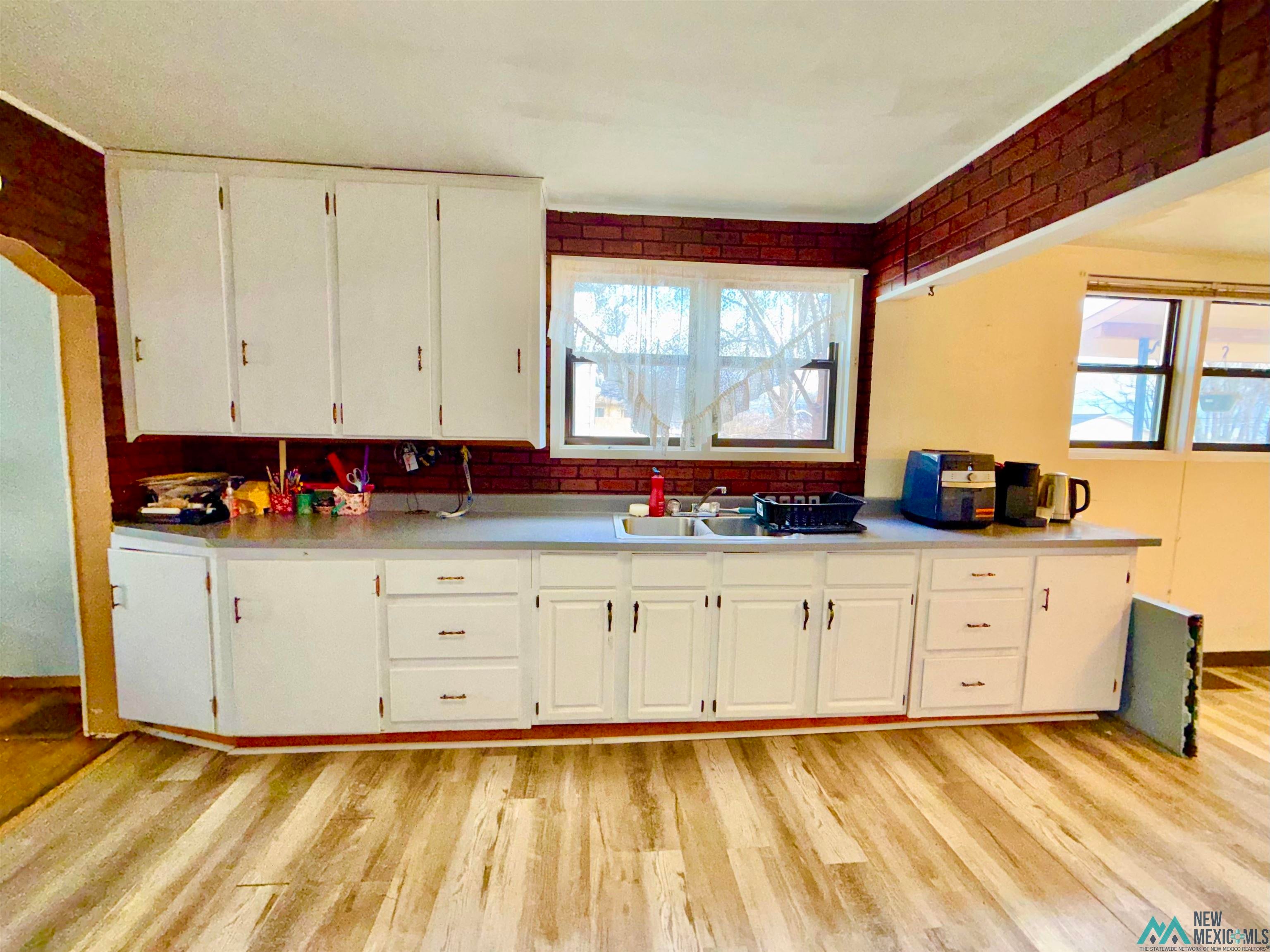 917 South 6th Street Raton, NM 87740 - Photo 7 of 35 Kitchen featuring light countertops, white cabinetry, and light wood-style floors