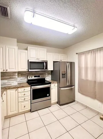 a kitchen with stainless steel appliances granite countertop a refrigerator and a stove top oven