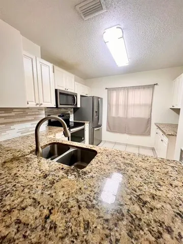 a kitchen with granite countertop a stove a sink and a microwave