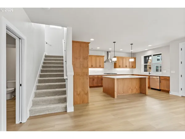 a large white kitchen with kitchen island a sink a stove a refrigerator and white cabinets