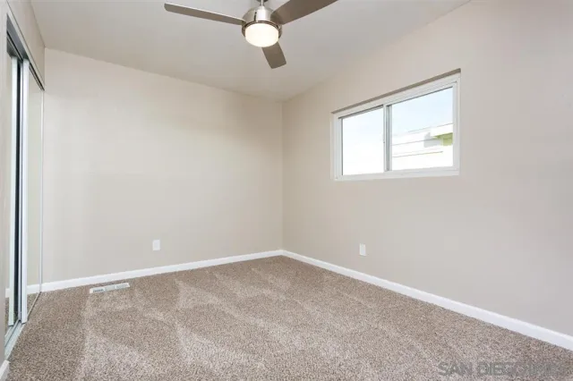 an empty room with a window and a fan