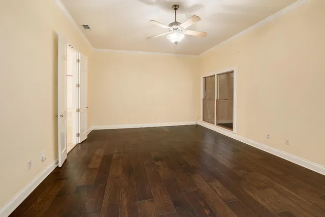 an empty room with wooden floor and ceiling fan