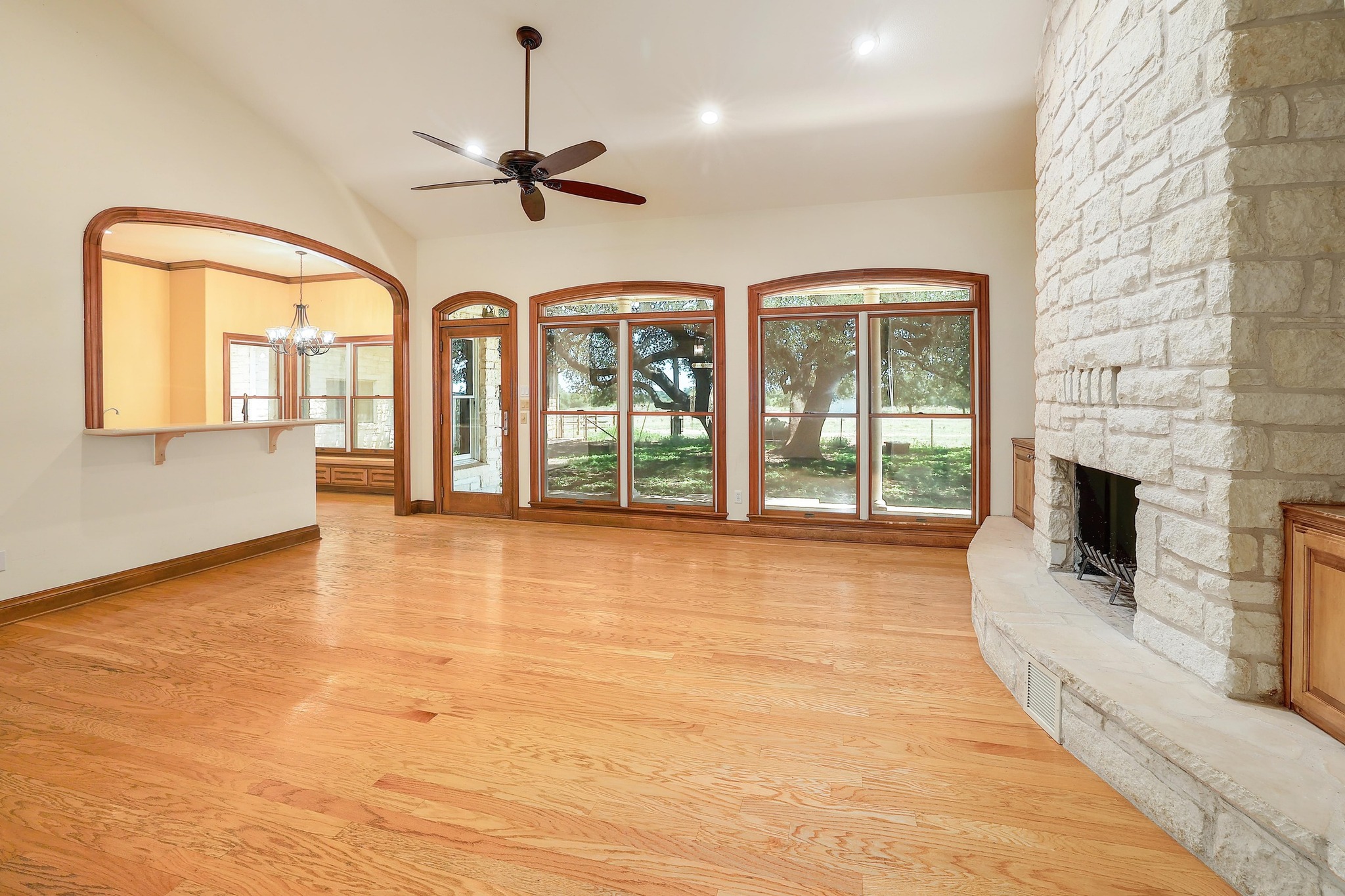 3900 Shell Road Georgetown, TX 78628 - Photo 6 of 40 Unfurnished living room featuring light wood finished floors, a stone fireplace, a chandelier, ceiling fan, and high vaulted ceiling