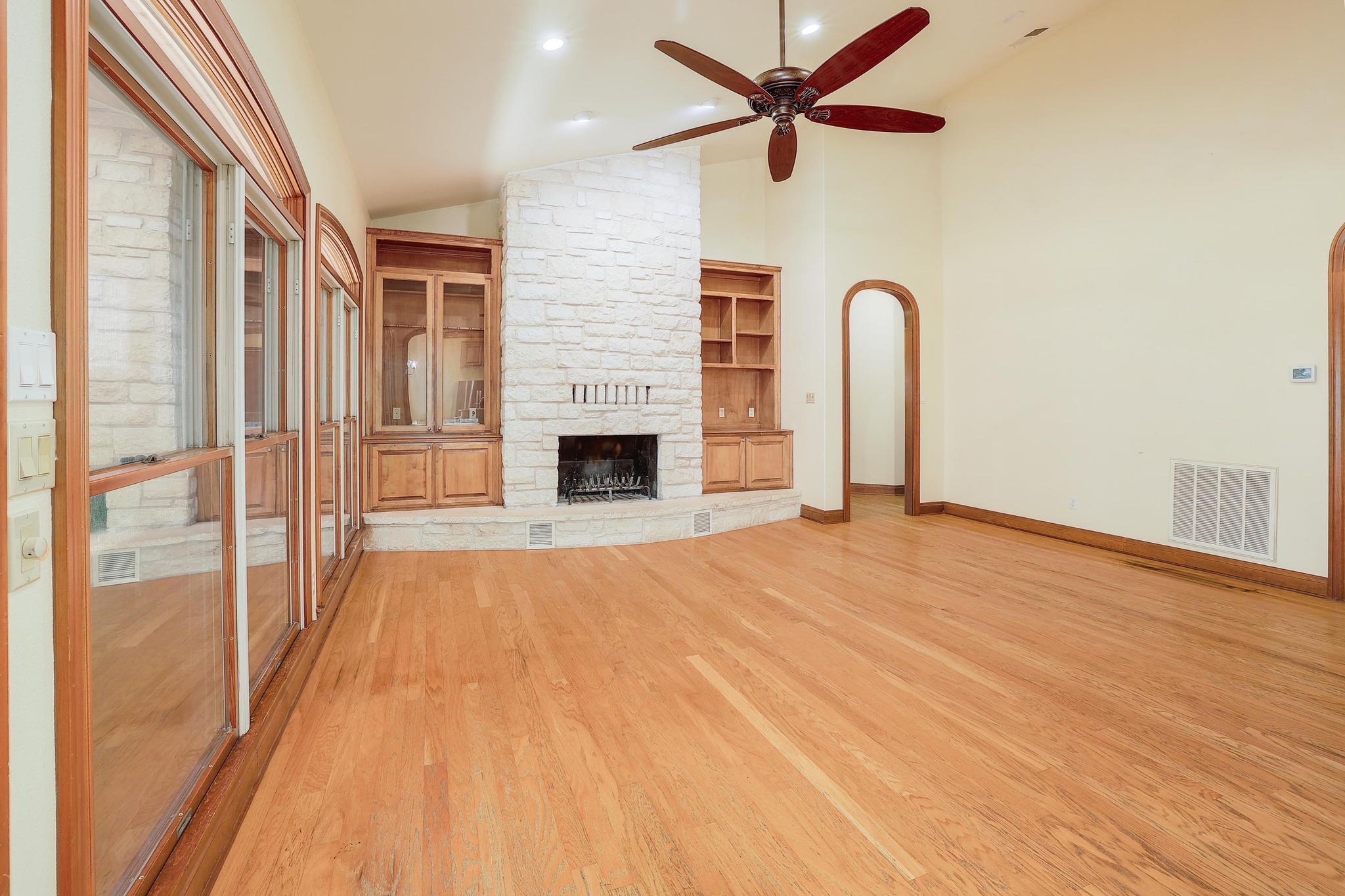 3900 Shell Road Georgetown, TX 78628 - Photo 7 of 40 Unfurnished living room featuring light wood-style flooring, a stone fireplace, a ceiling fan, high vaulted ceiling, and built in features