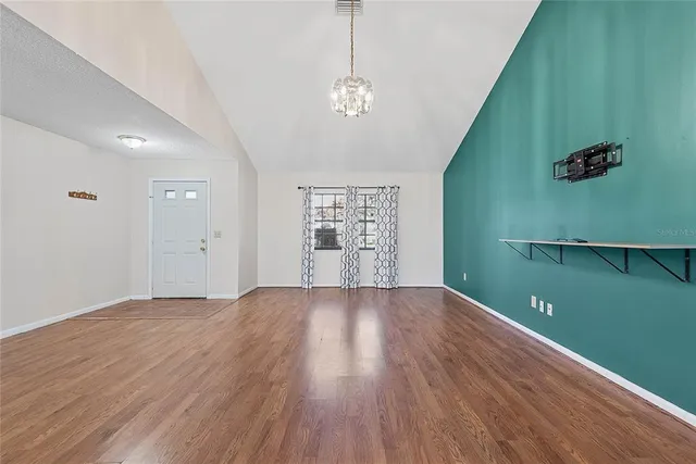 a view of an empty room with window and wooden floor