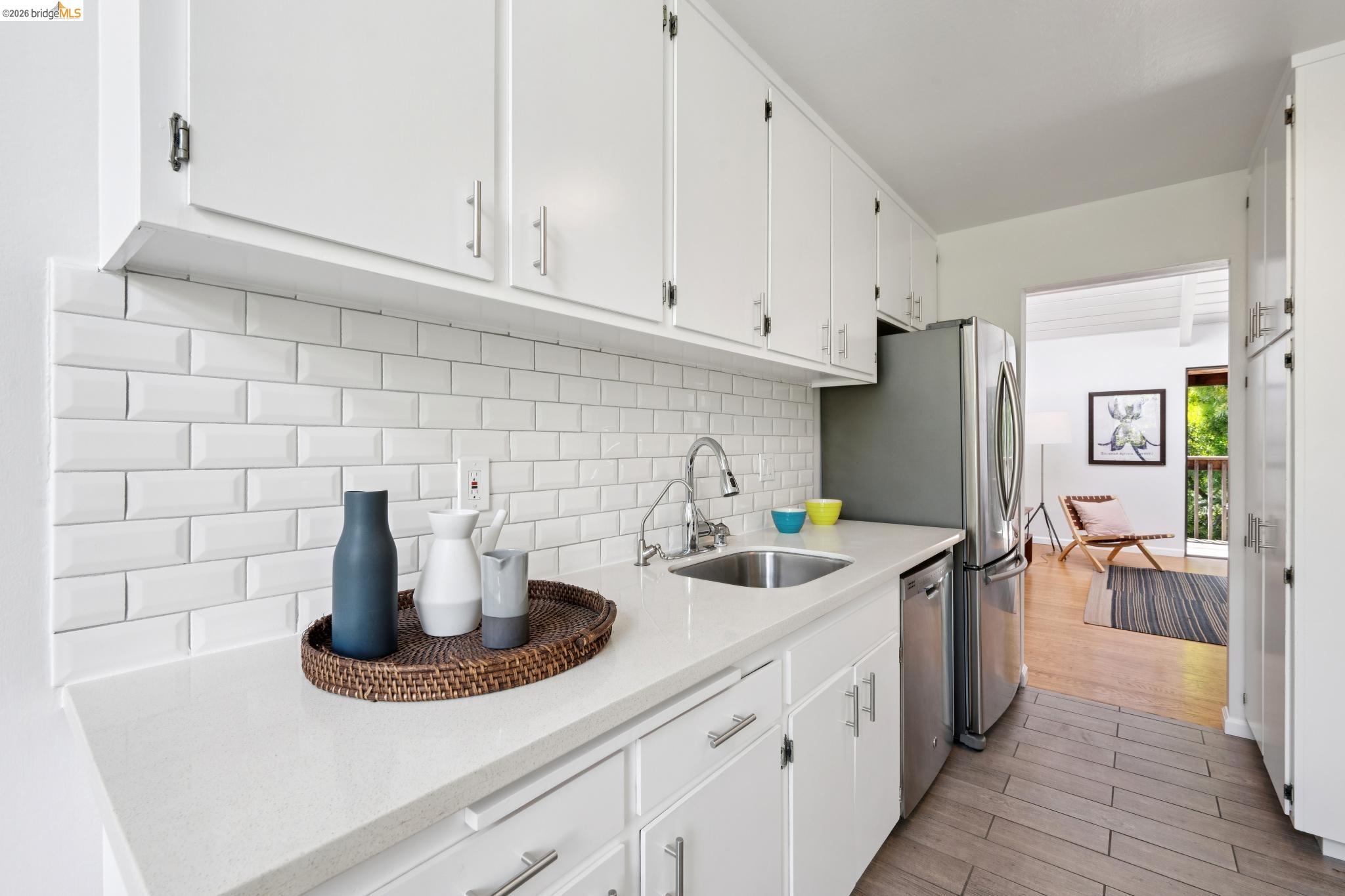 1340 Henry Street Berkeley, CA 94709 - Photo 22 of 52 Kitchen featuring white cabinetry, light-toned countertops, a white subway tile backsplash, stainless steel appliances, and wood-finish flooring