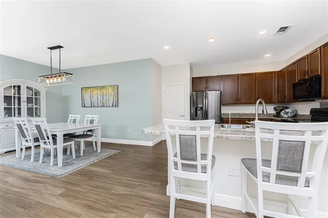 a kitchen with stainless steel appliances wooden floor dining table and chairs