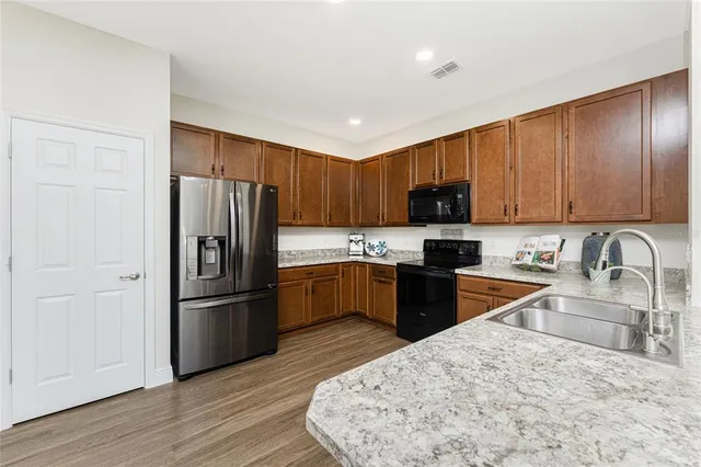 a kitchen with granite countertop wooden cabinets a refrigerator stove and wooden floor