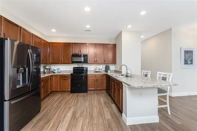 a large kitchen with stainless steel appliances granite countertop a refrigerator a sink dishwasher a stove with wooden cabinets and floor